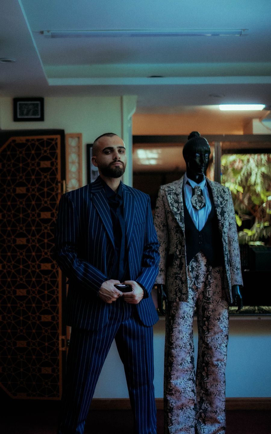 Hombre elegante con traje rayado junto a un maniquí